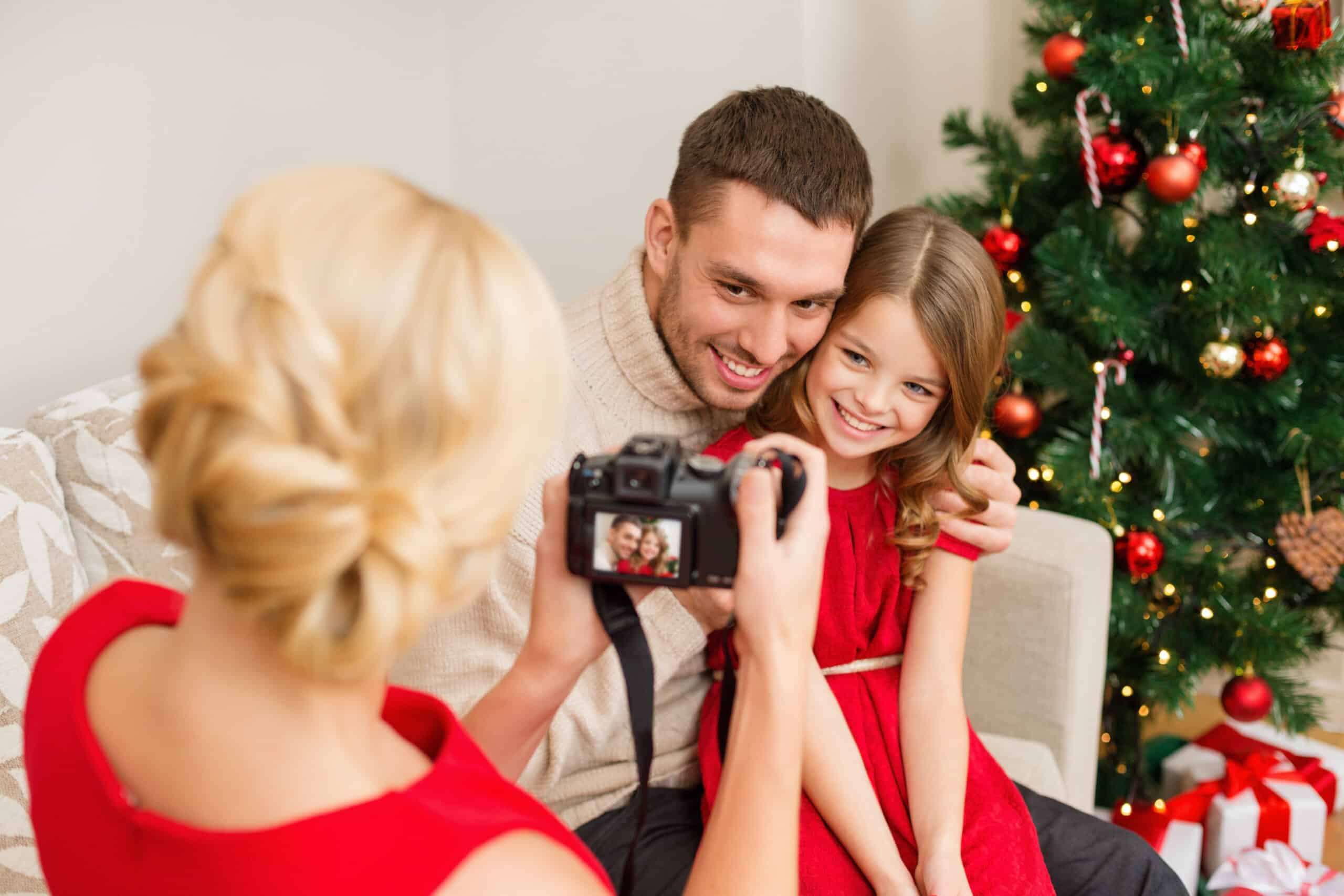 family, christmas, x-mas, winter, happiness and people concept – mother taking picture of smiling father and daughter